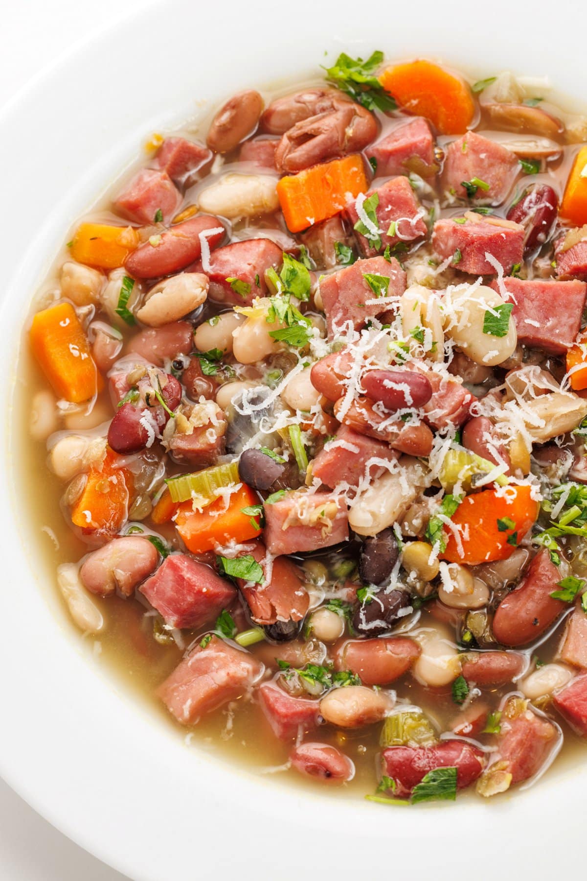 15 bean soup with ham garnished with parmesan cheese and fresh herbs.