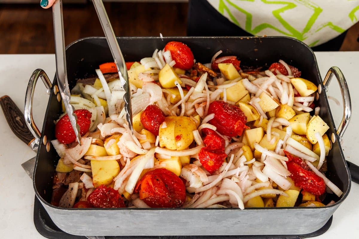 Tossing ingredients for beef brisket in the sauce in the pan.