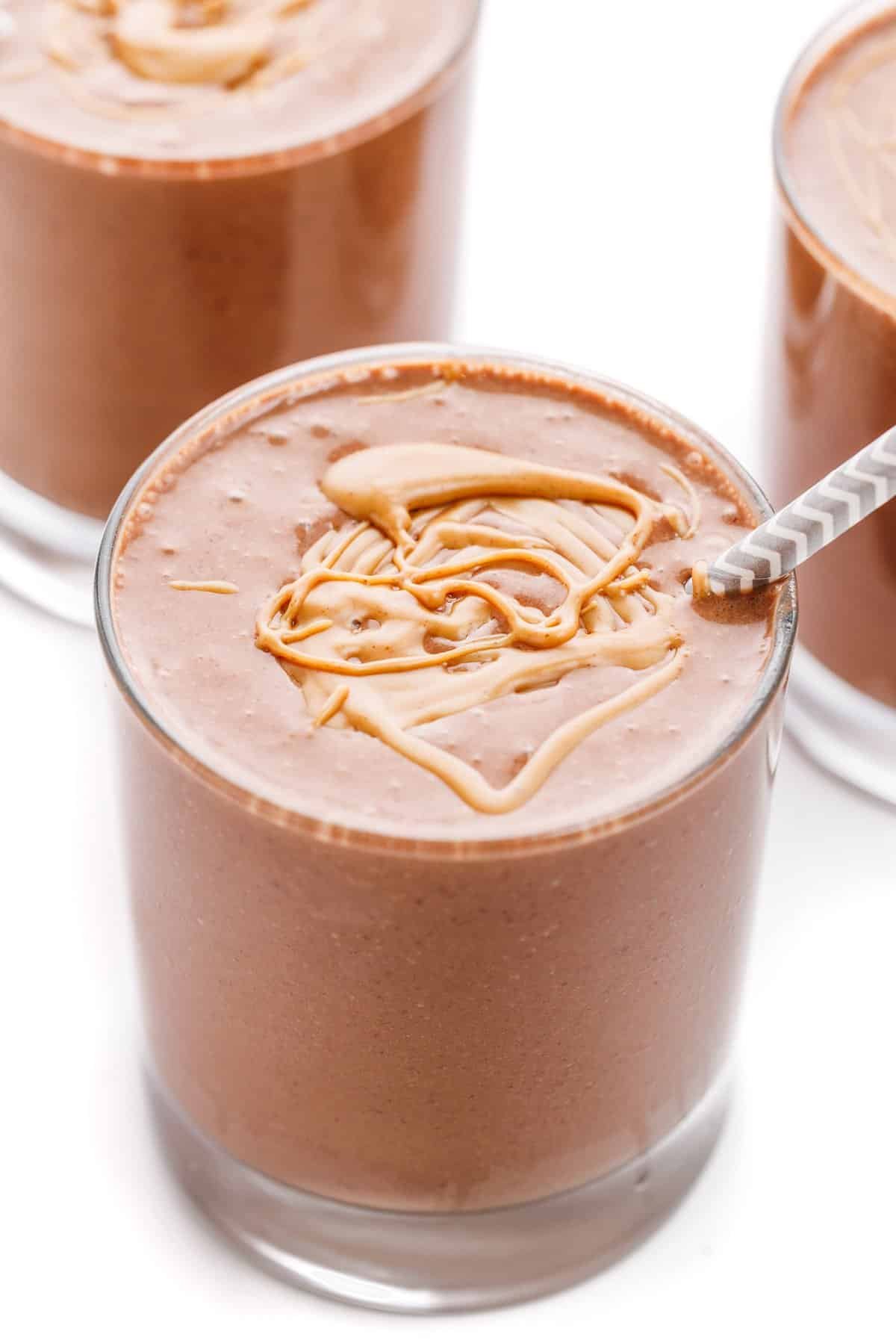 A chocolate peanut butter protein smoothie with peanut butter drizzled over the top.