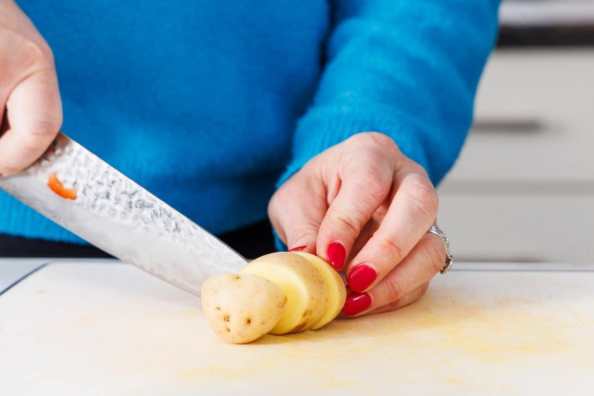 Liz cutting a potato on a cutting board.