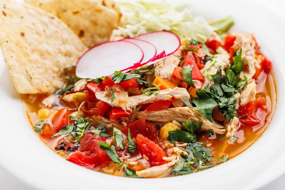 Mexican chicken pozole soup in a white bowl.