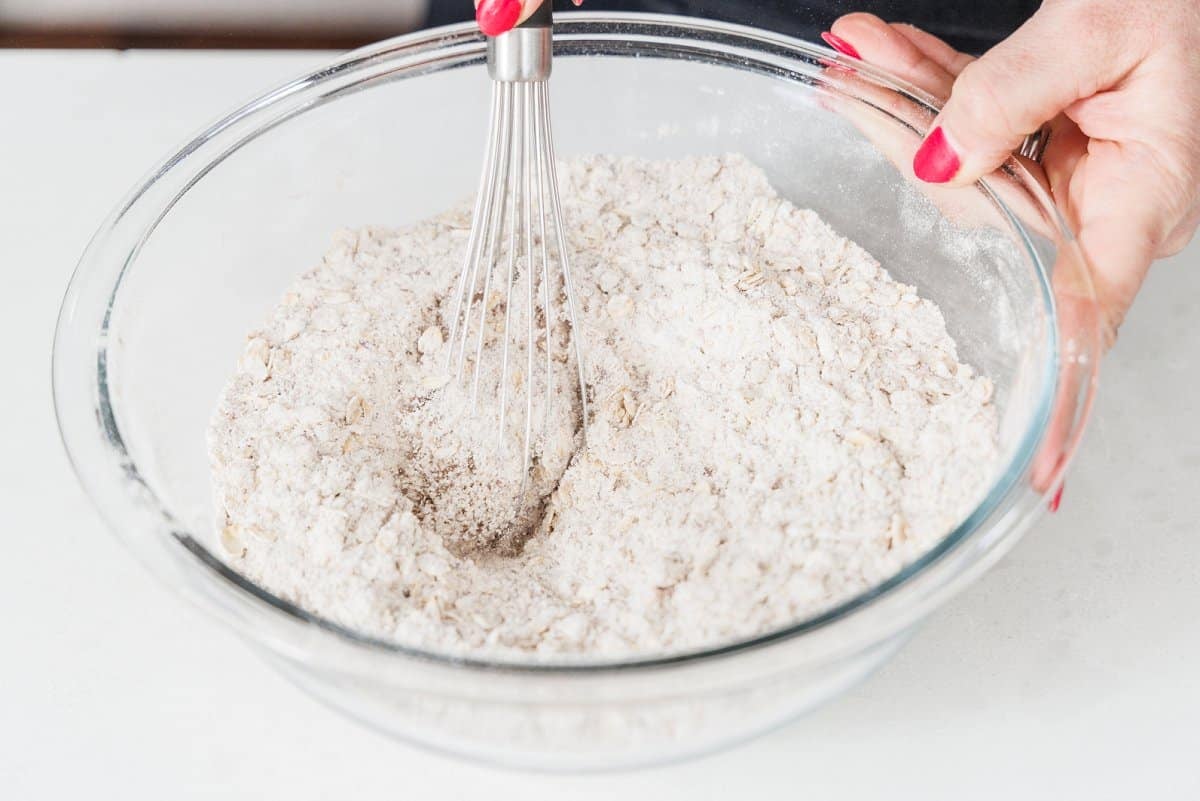 Whisking dry ingredients together in a large glass bowl.