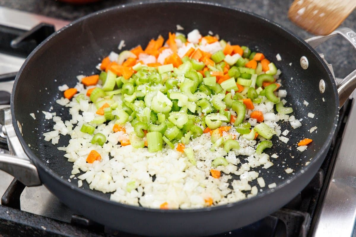 Cooking onion, celery, and carrots in a pan.