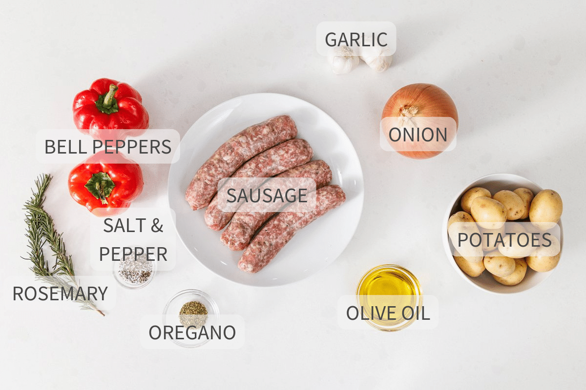 Labeled ingredients for sheet pan sausage, peppers, and potatoes on a white backdrop.