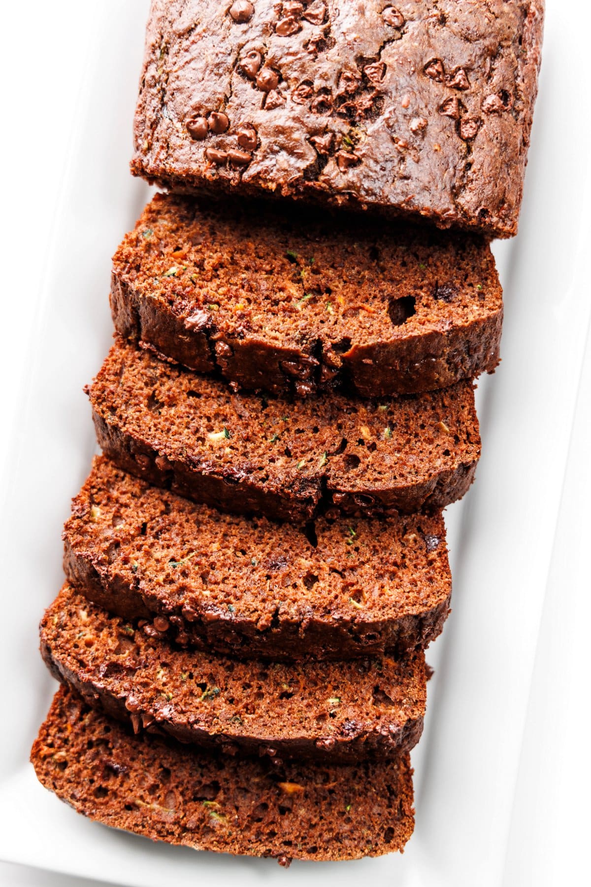 Chocolate zucchini carrot bread sliced on a white platter.