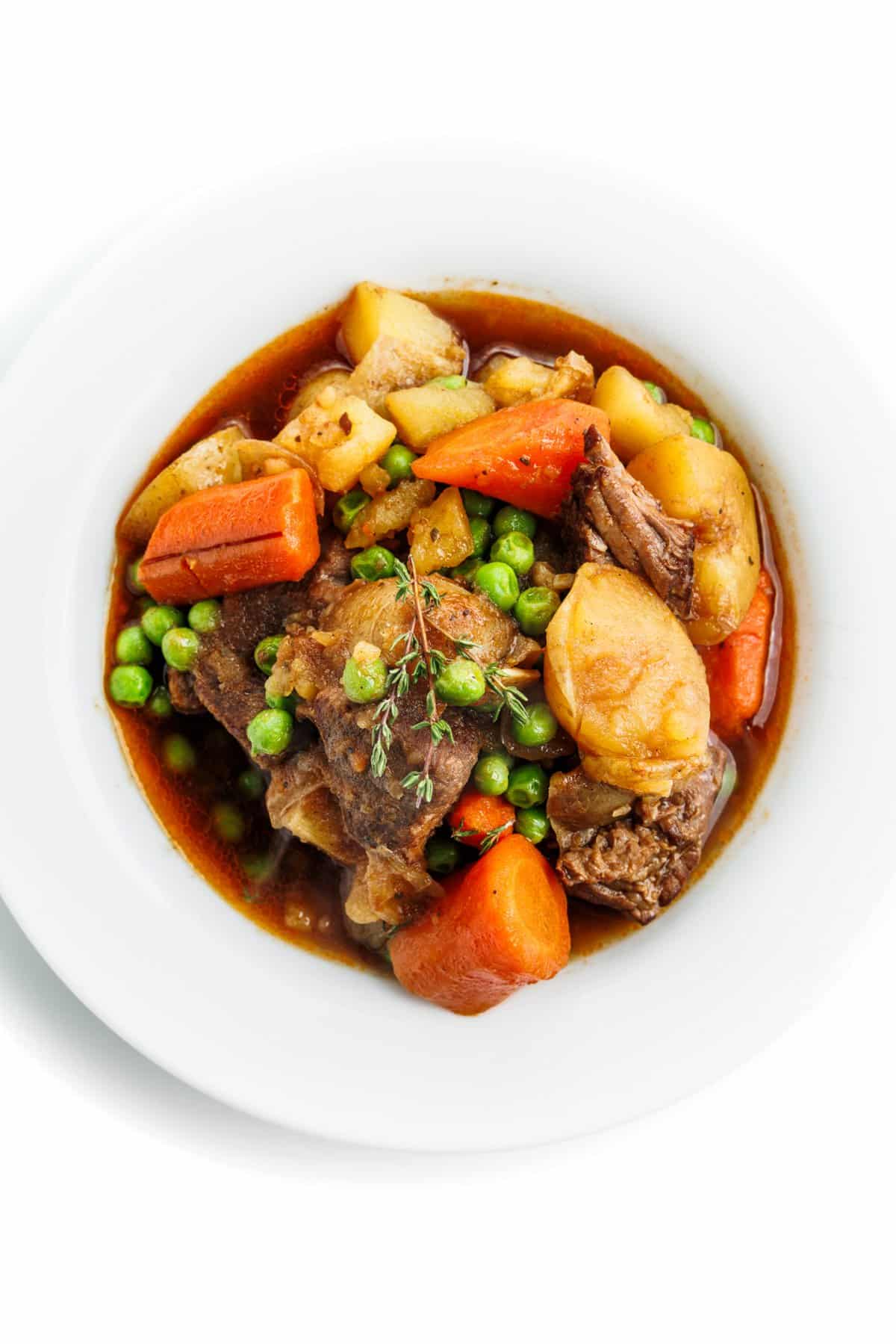 A white shallow bowl filled with slow cooker Irish beef stew.
