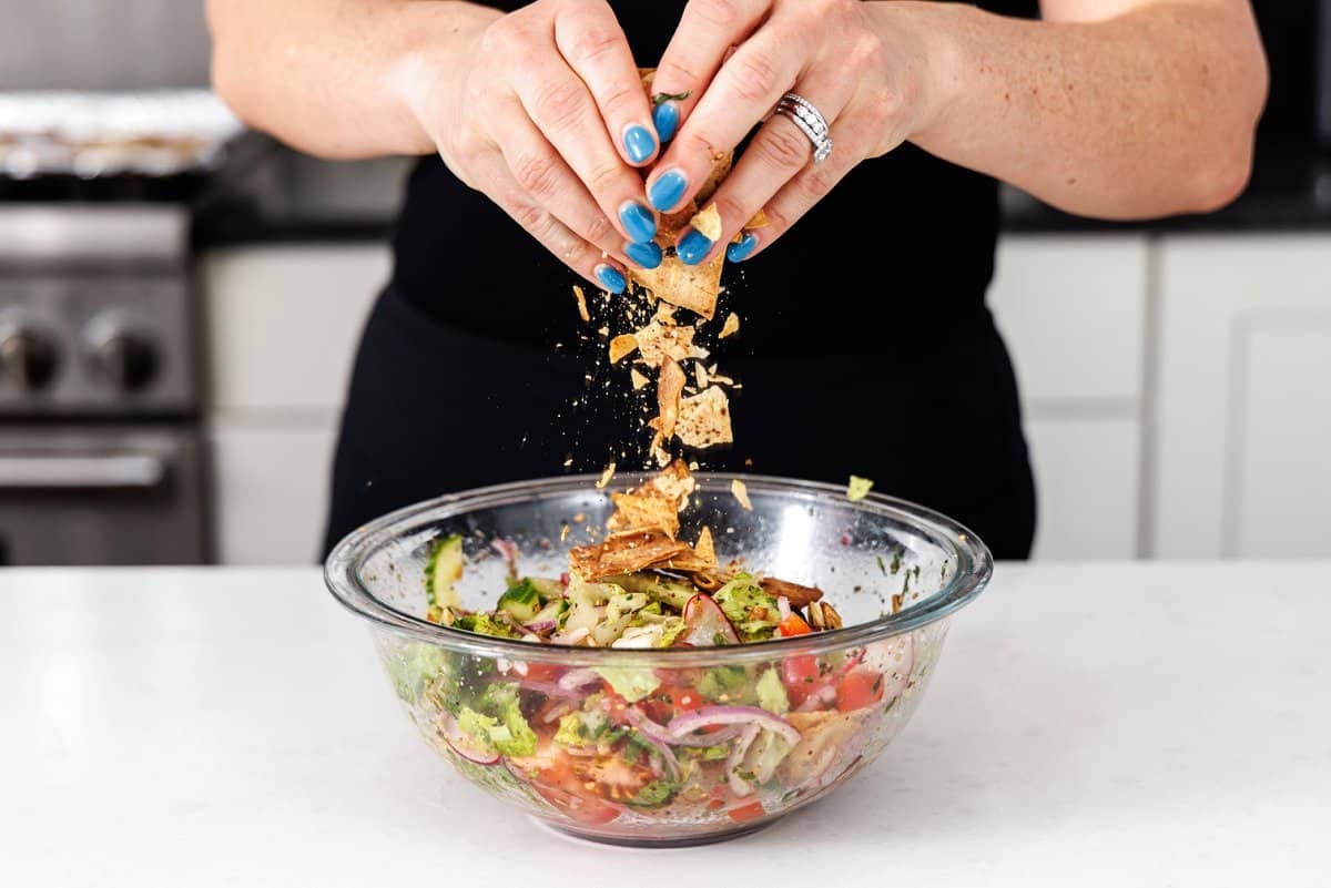 Breaking up baked pita chips over top a Lebanese salad.