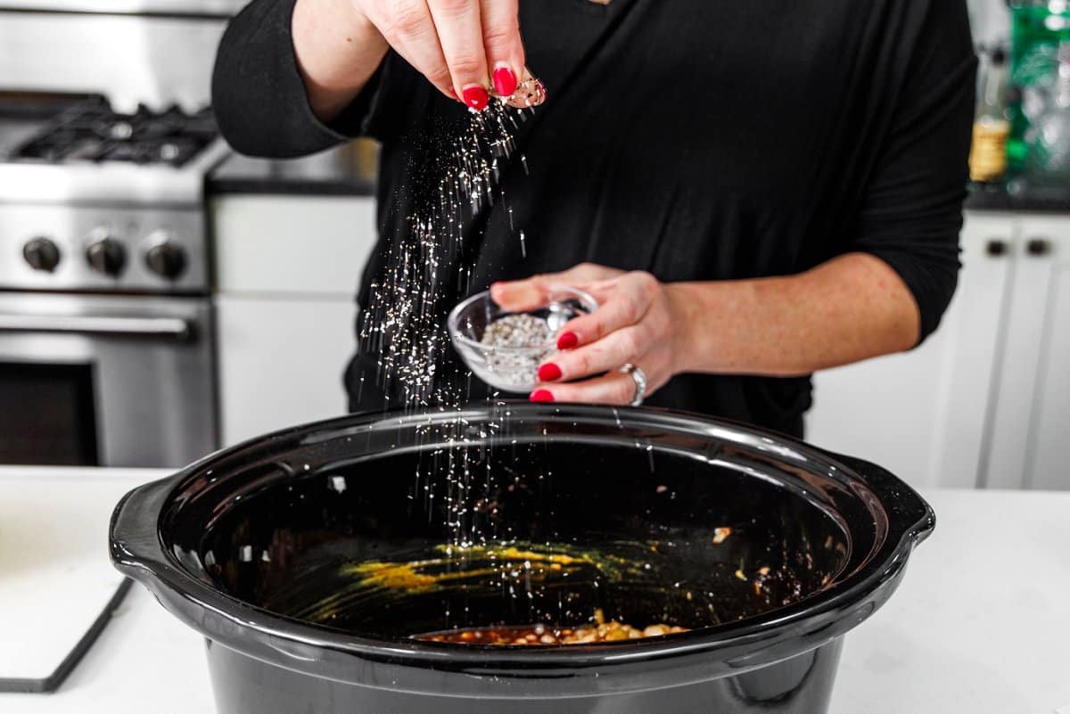 Seasoning beans in the bowl of a slow cooker.