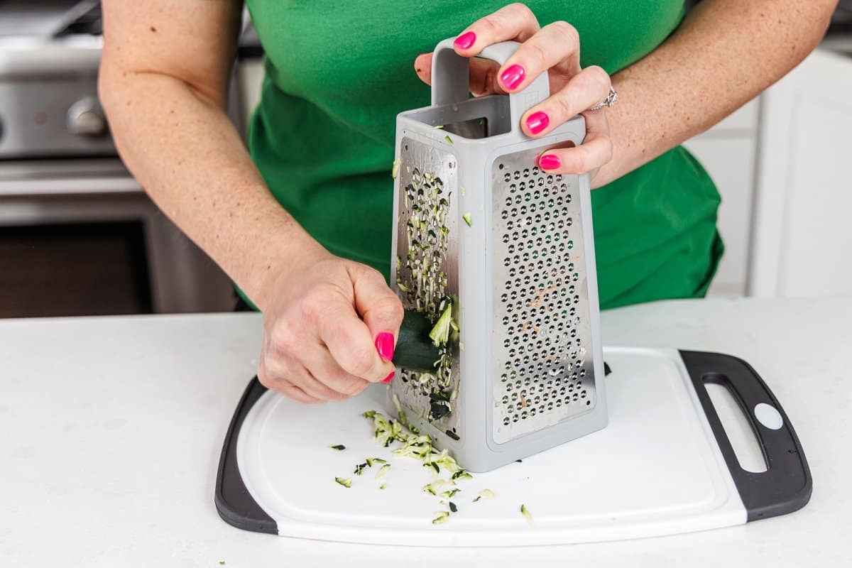 Grating a zucchini on a cutting board.
