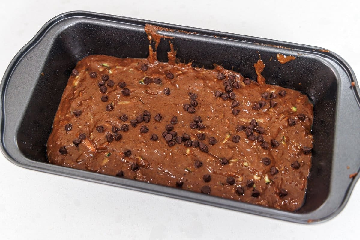 Chocolate bread batter in bread tin topped with chocolate chips.