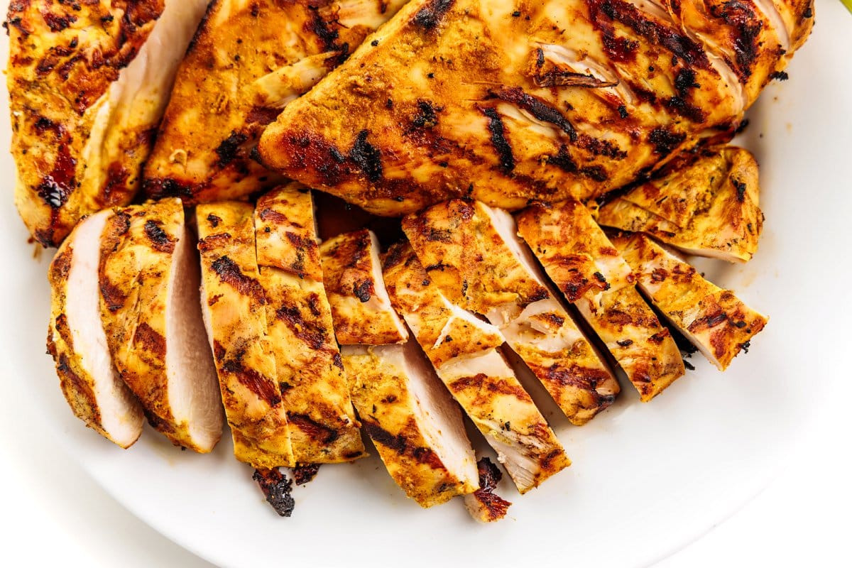 Sliced Indian spiced grilled chicken on a white plate.