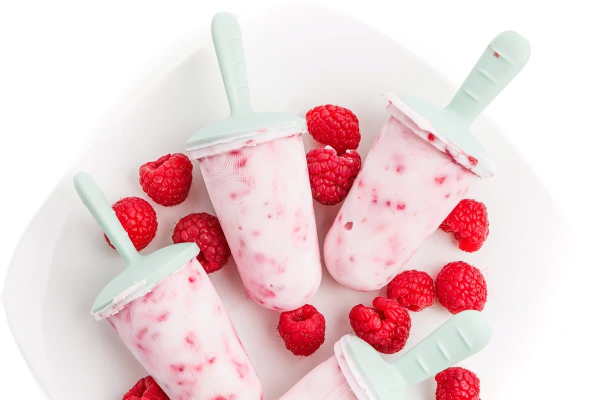 Greek yogurt raspberry popsicles demolded on plate.