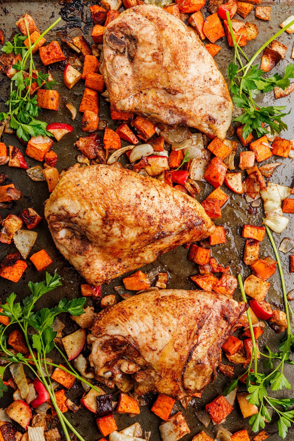 Close up of sheet pan chicken and sweet potatoes still on the pan.