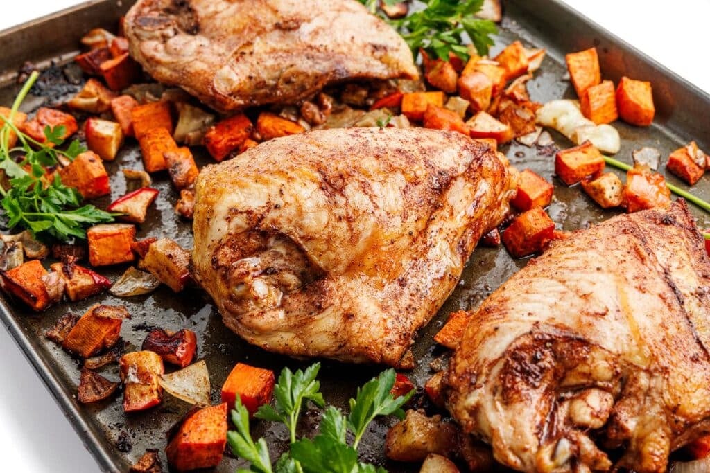 Sheet pan chicken and sweet potatoes with fresh parsley.
