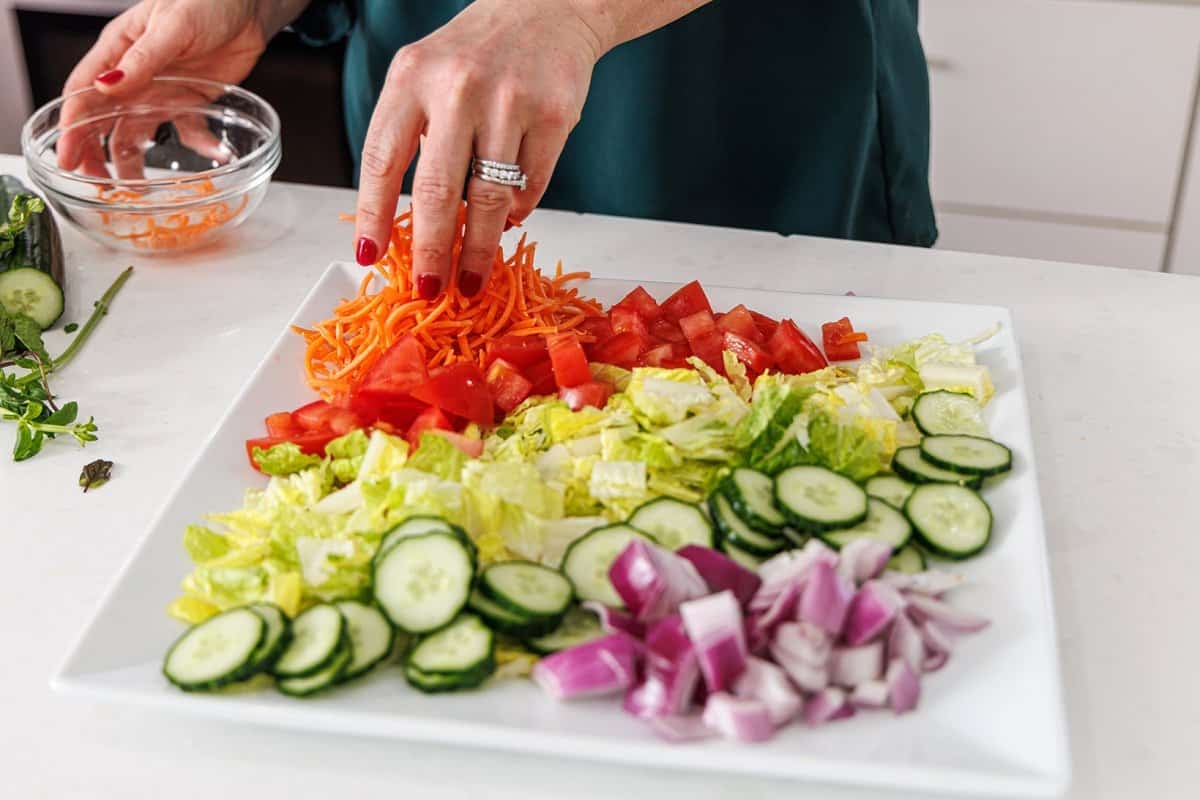 Arranging salad ingredients on plate.