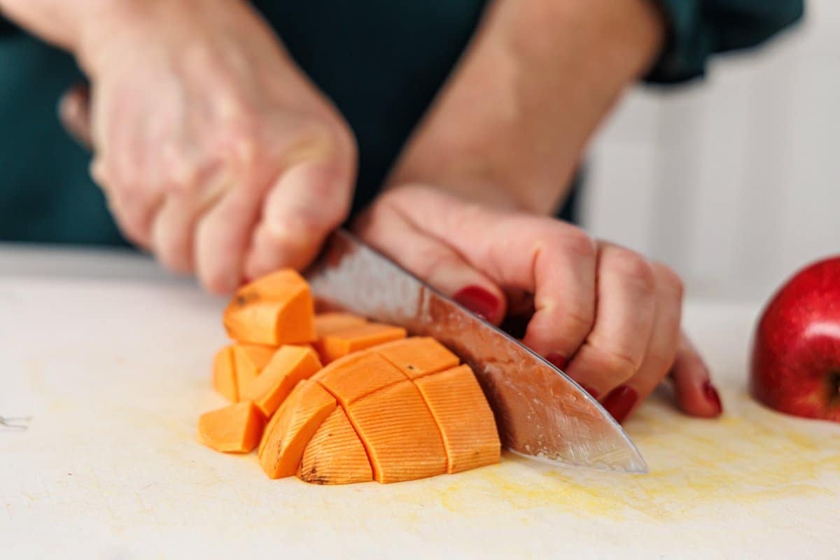 Liz dicing a peeled sweet potato.
