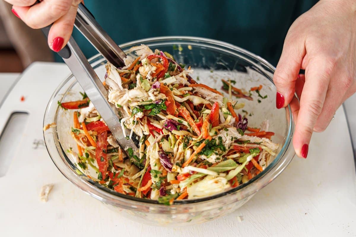 Tossing Asian chopped salad in bowl.