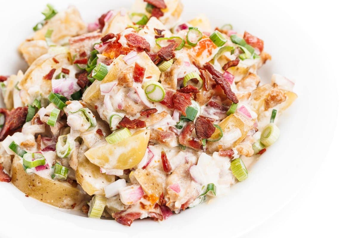 Potato salad with bacon and eggs topped with chives.