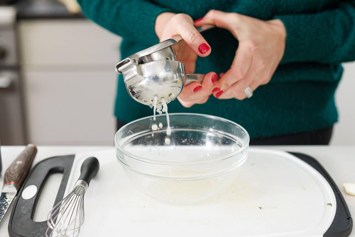 Using a citrus juicer to juice a lemon into a bowl.