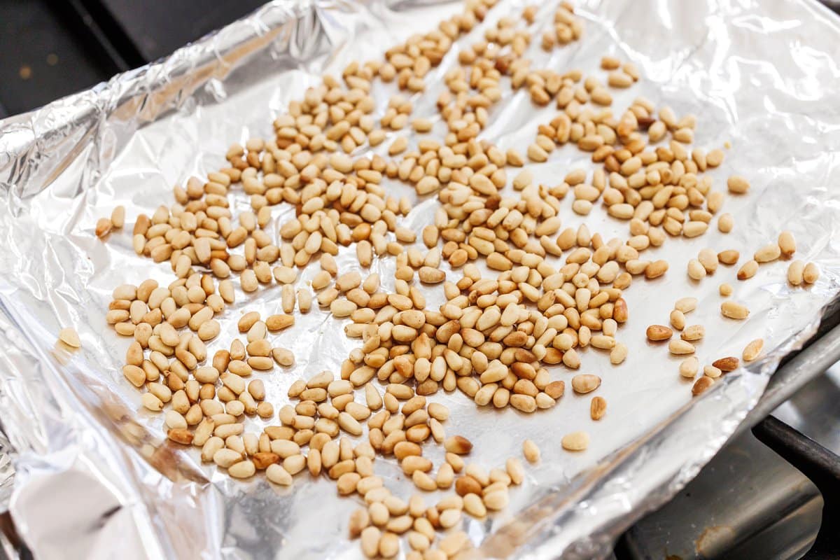 Toasting pine nuts on a sheet pan covered in tin foil.