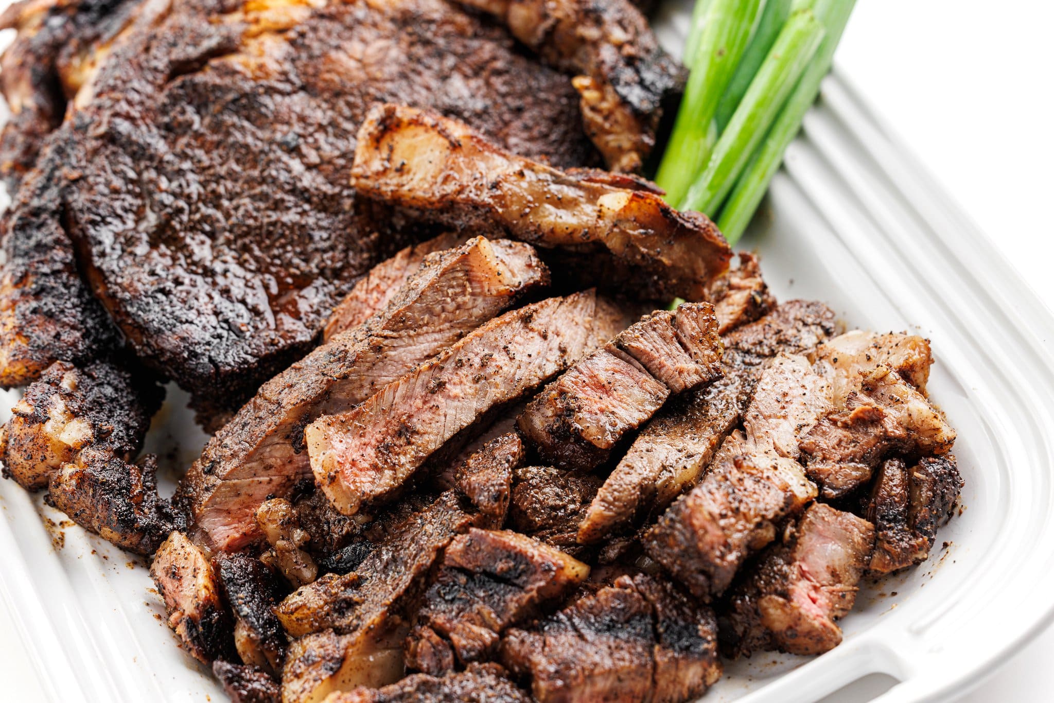 Cut strips of coffee crusted ribeye on a platter.