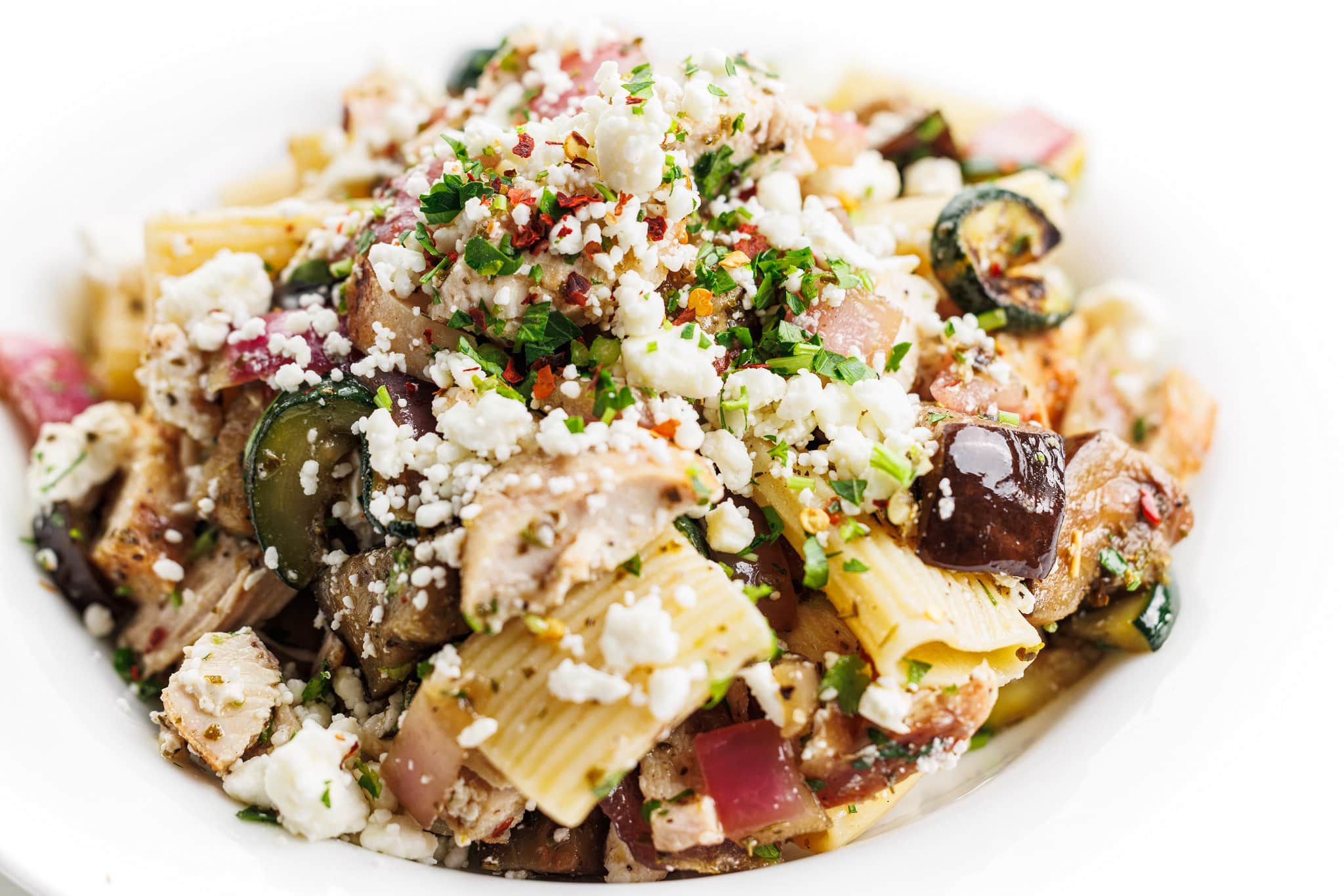 Wide angle view of grilled chicken and vegetable pasta salad.
