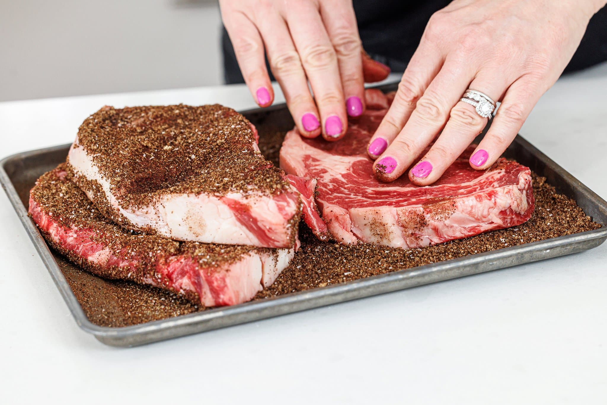 Rubbing coffee spice rub on both sides of ribeyes.