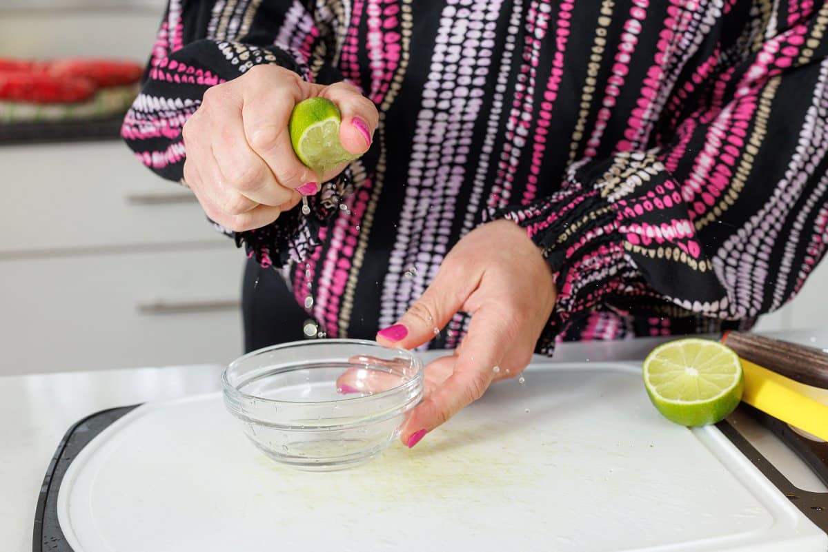 Juicing a lime into a small glass bowl.