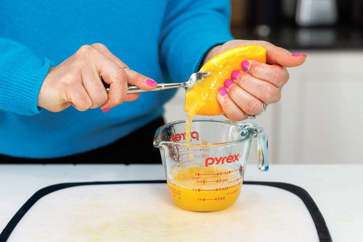 Using a fork to juice an orange into a liquid measuring cup.