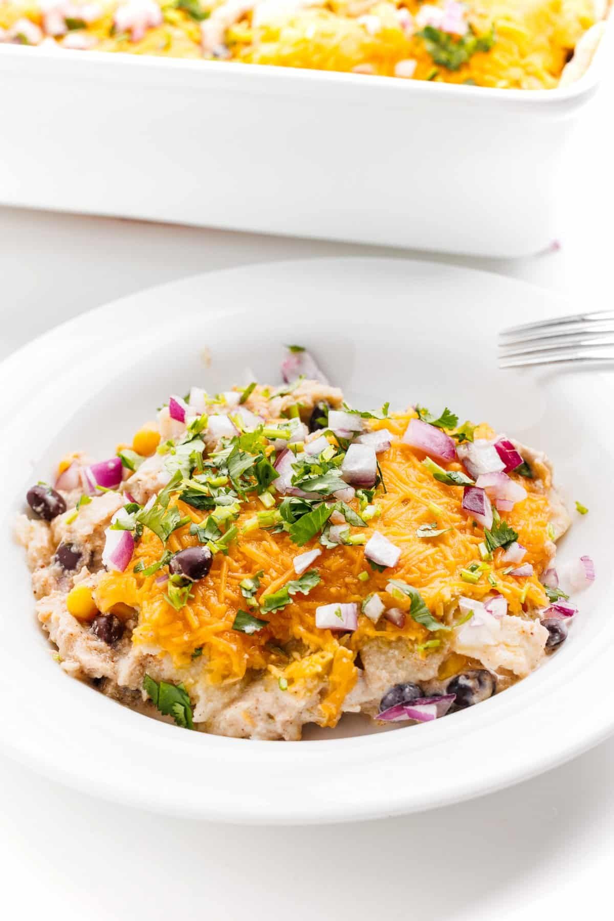 Mexican lasagna with chicken and beans served on a white plate.