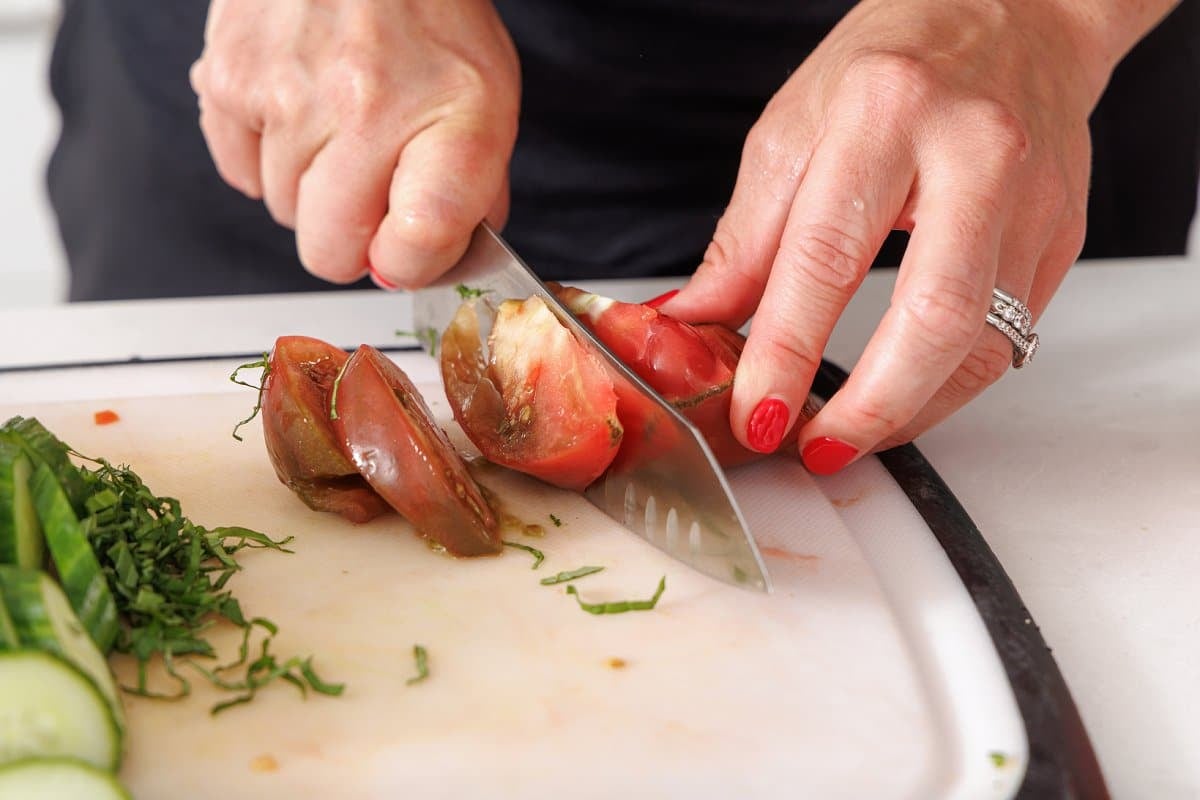 Slicing heirloom tomatoes on a cutting board.