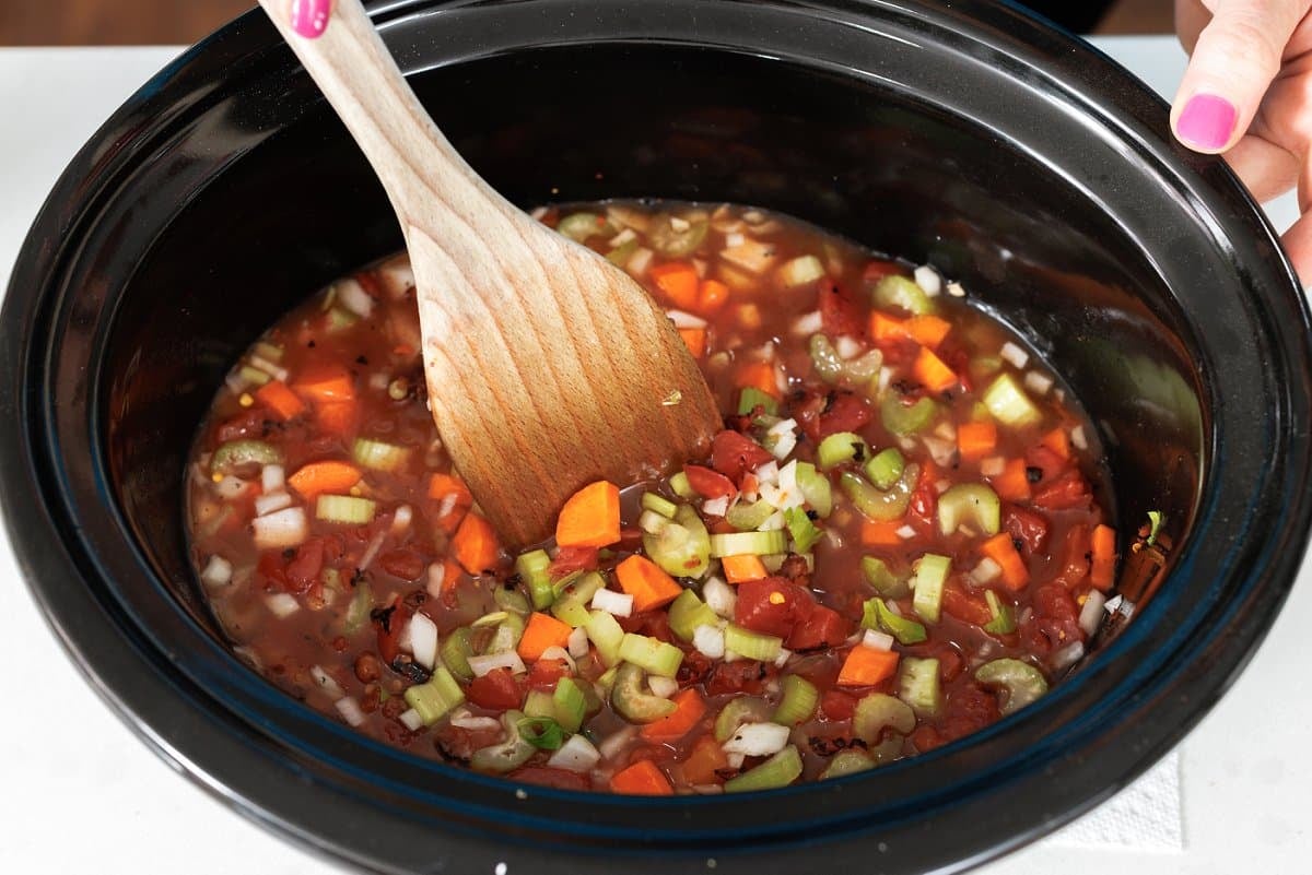 Stirring lentil soup in slow cooker pot.