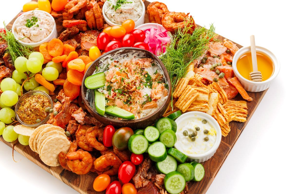 Seacuterie (smoked fish charcuterie board) spread with fresh veggies, crackers, smoked fish, and fish dips.