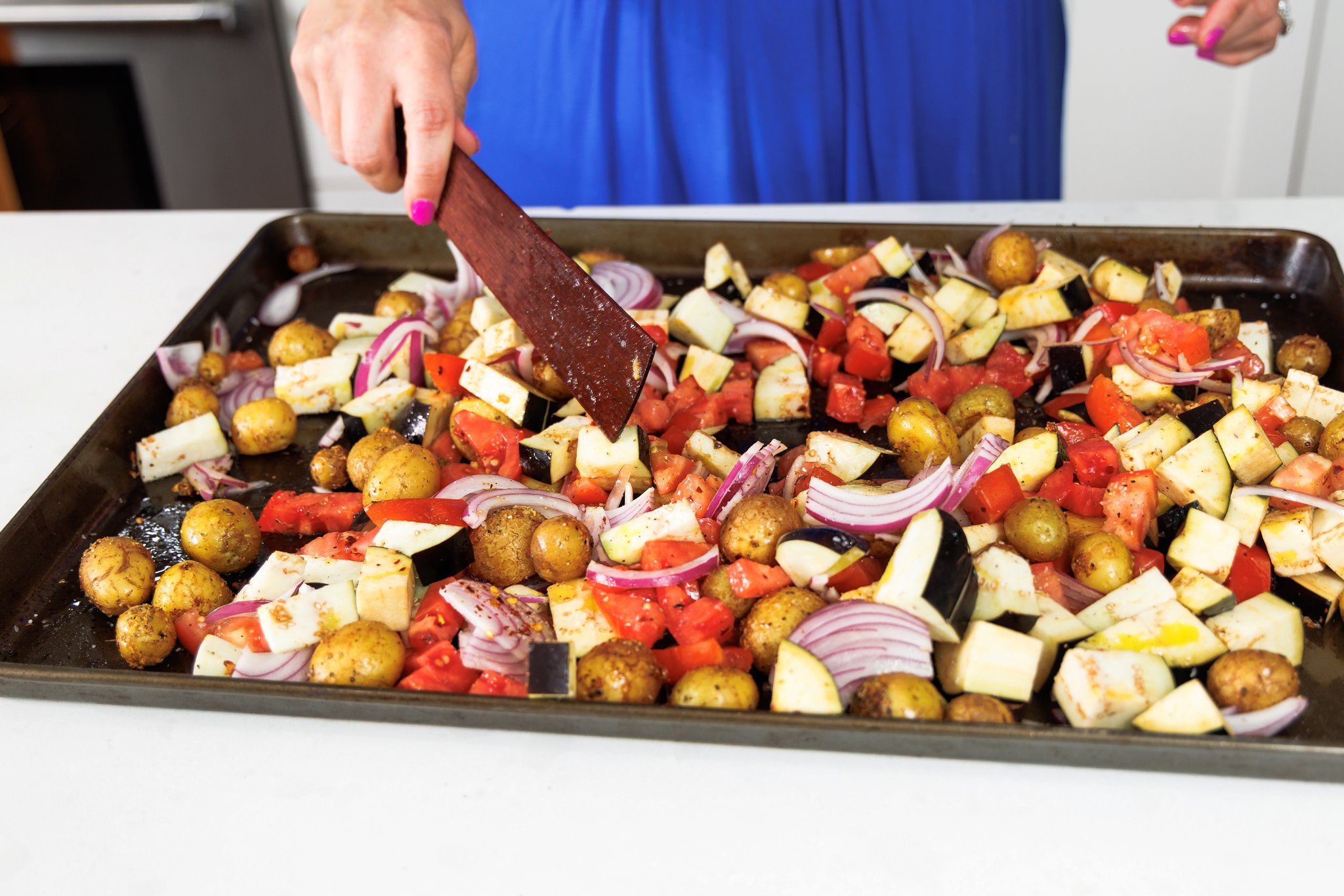 Spreading cut veggies evenly on a sheet pan.