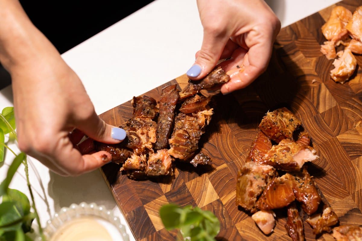 Laying out smoked salmon jerky on a large cutting board.