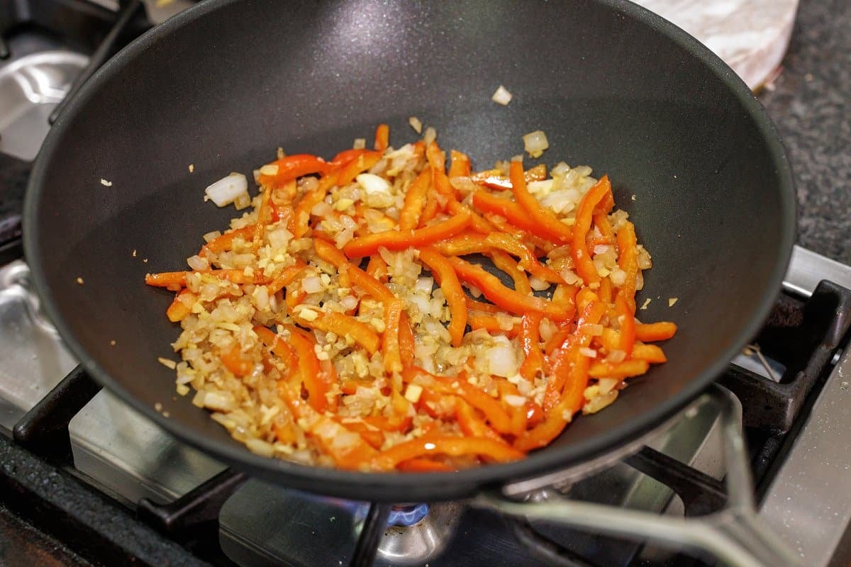 Cooking onion and bell pepper in wok.