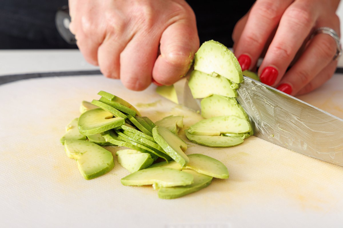 Cutting avocado into very thin slices.