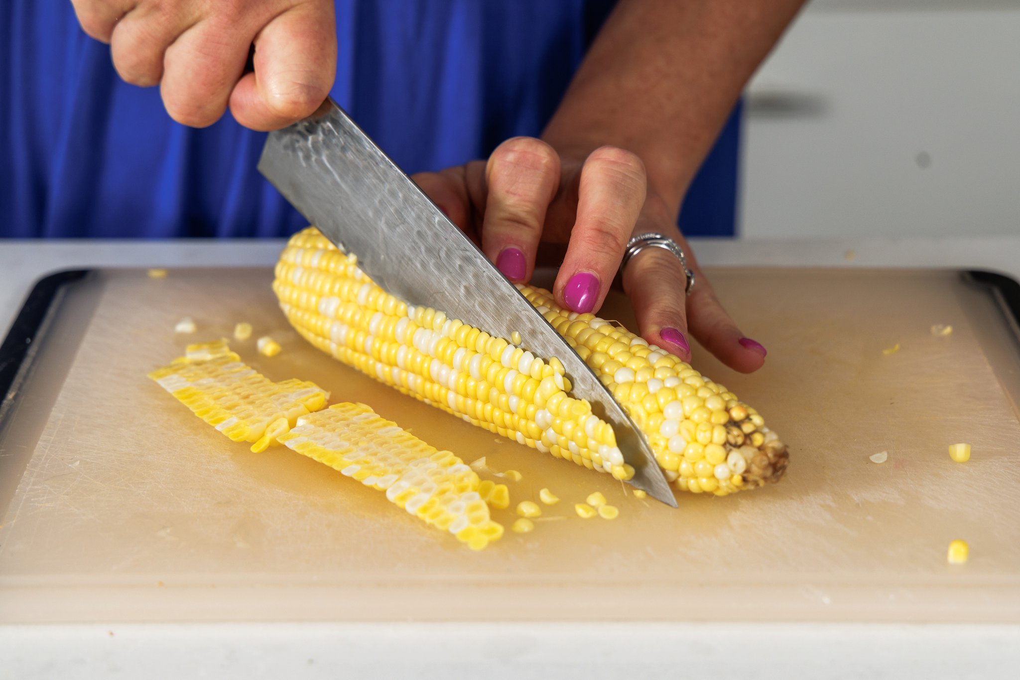Cutting corn off of corn cob.
