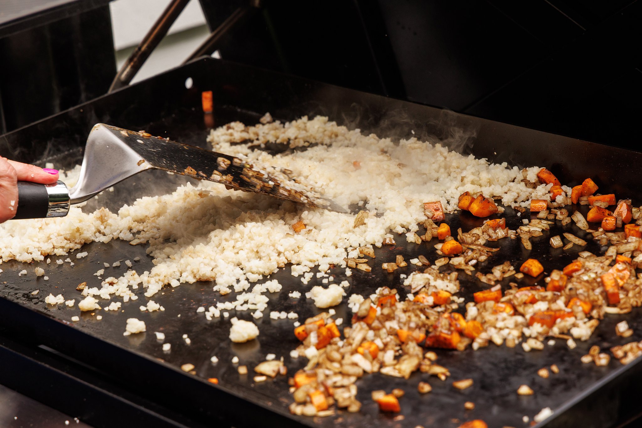 Cooking veggies and cauliflower rice on griddle.
