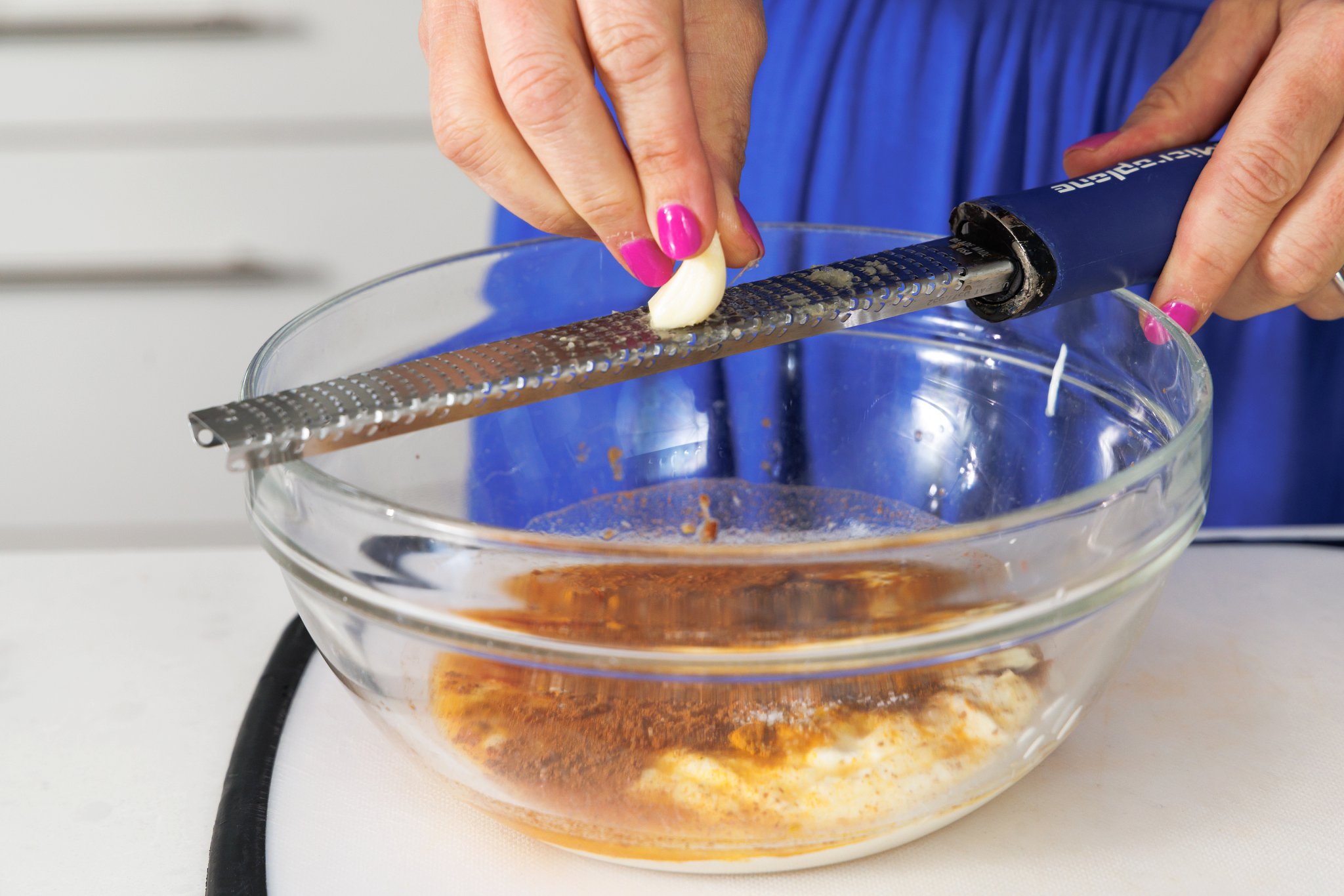 Grating garlic into a bowl with marinade.