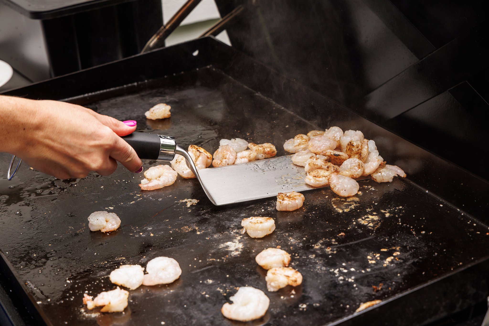 Cooking shrimp on an outdoor griddle.