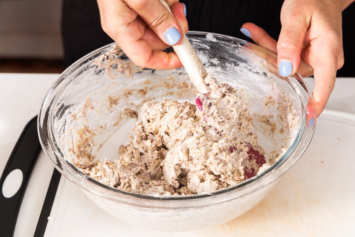 Mixing muffin batter with a spatula in a bowl.