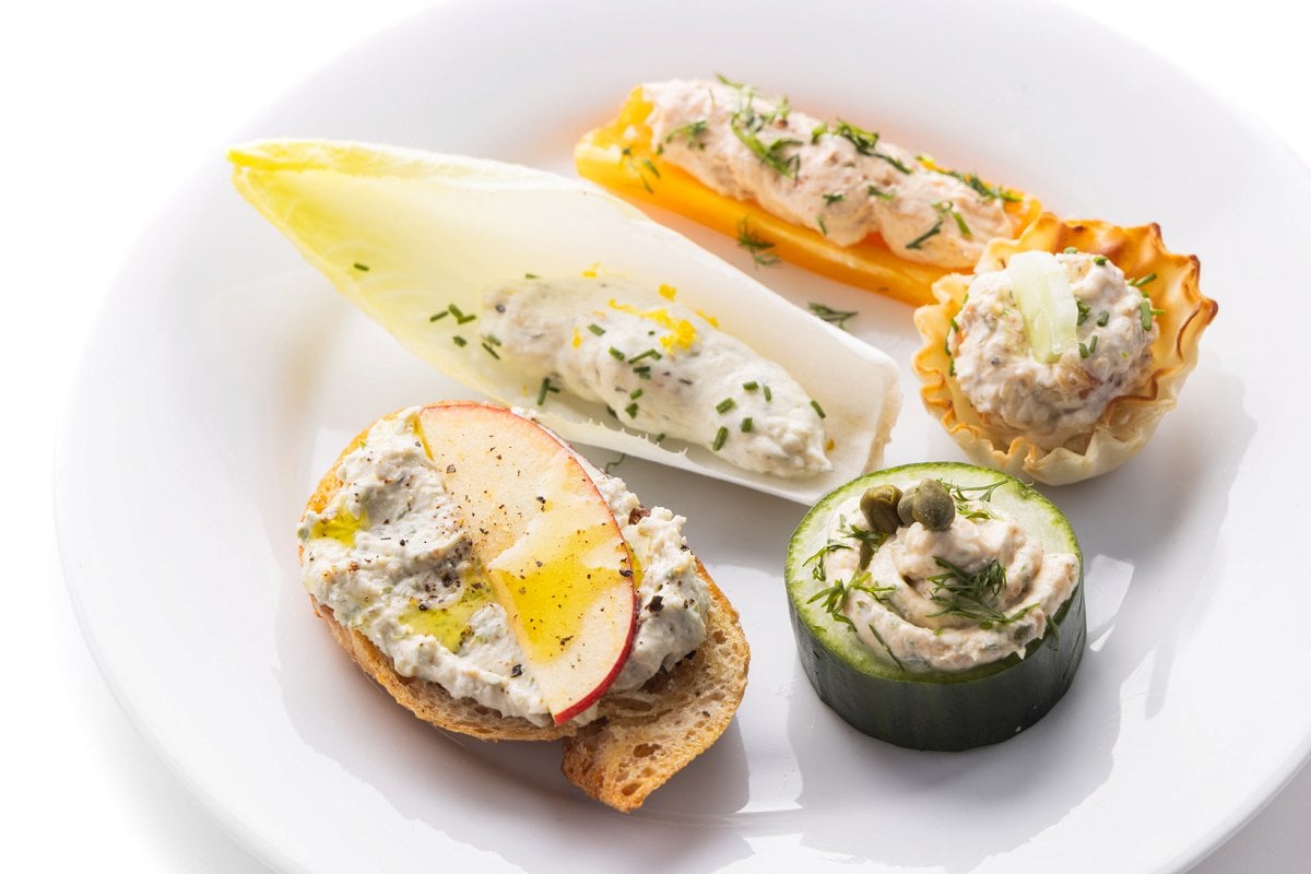 Plate with no-cook holiday appetizers with smoked fish dip, including cucumber round and endive leaf.