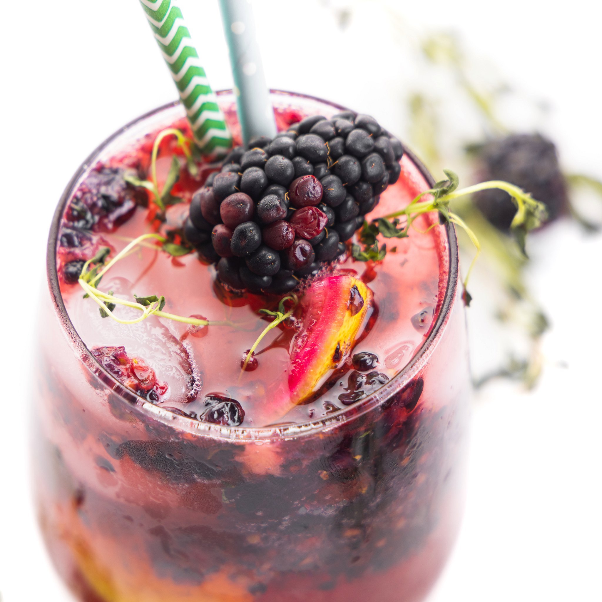 Close up view of a blackberry floating on top of a blackberry ginger smash mocktail.