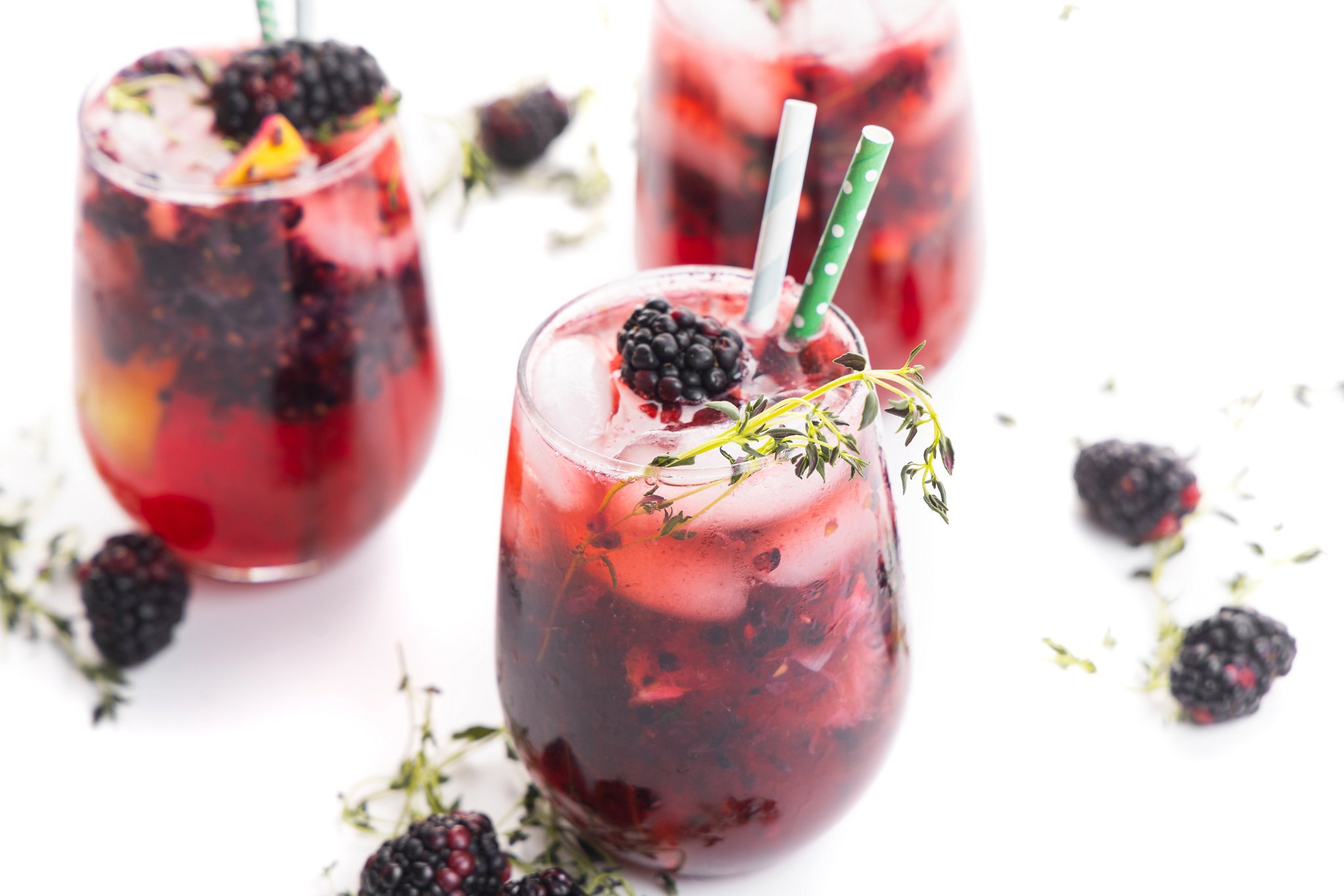 Three blackberry ginger smash cocktails garnished with thyme sprigs and blackberries.