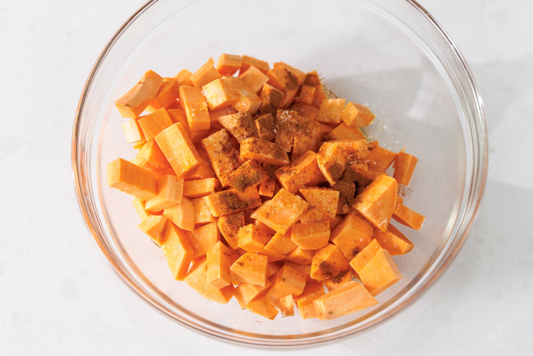 Chopped sweet potatoes in a bowl with cinnamon.