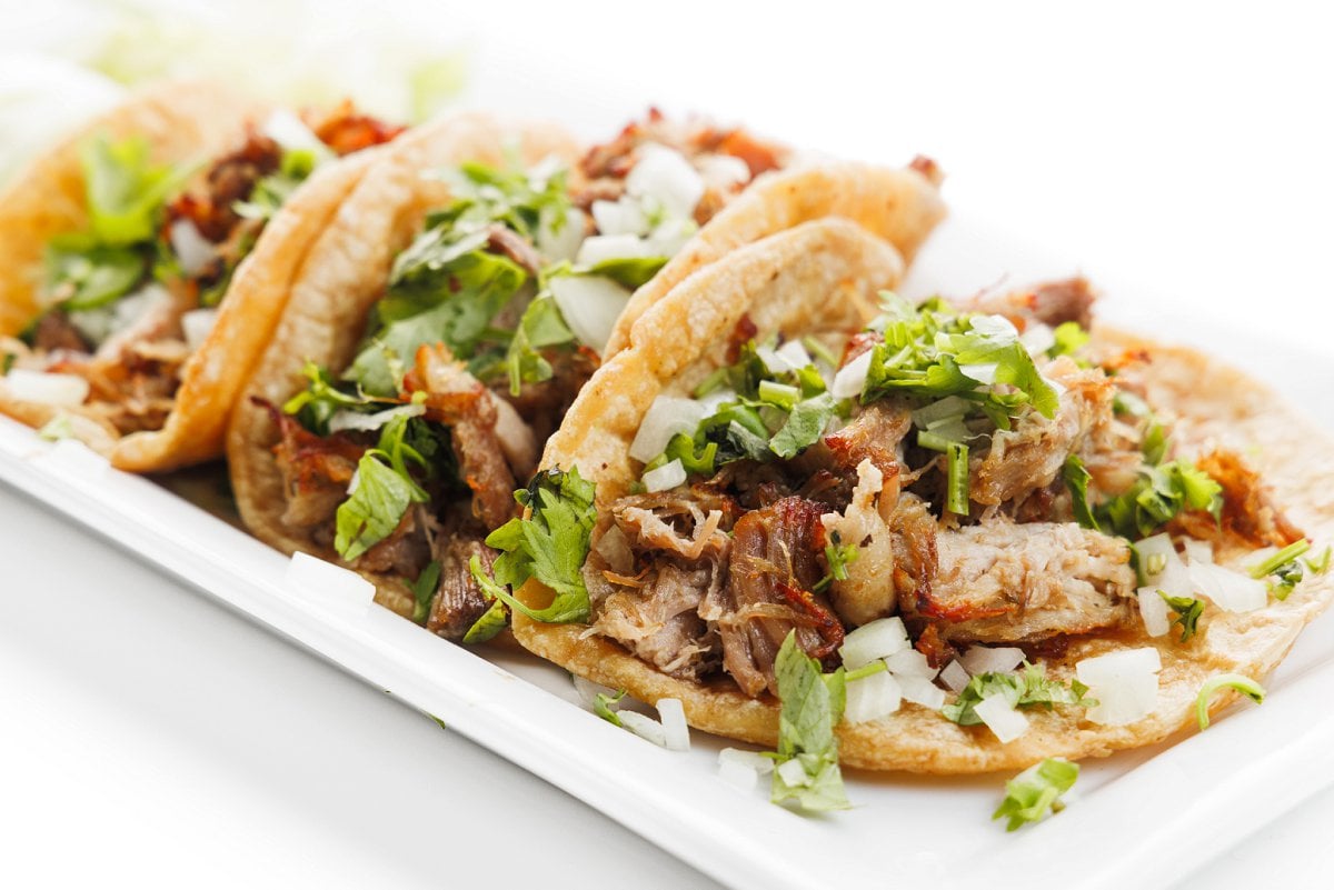 Slow cooker pork carnitas in tacos on a plate.