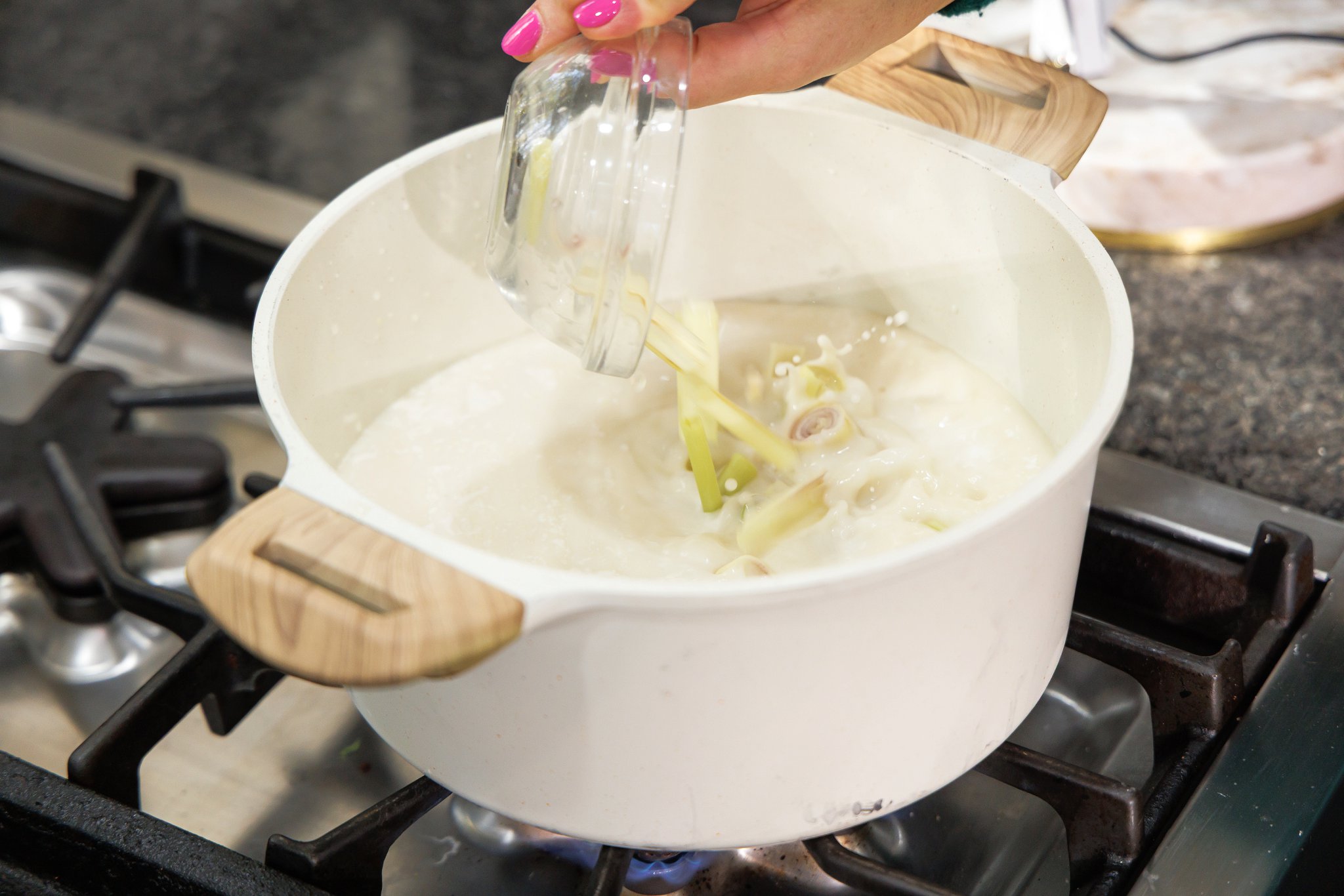 Adding cut lemongrass stalks to soup pot.