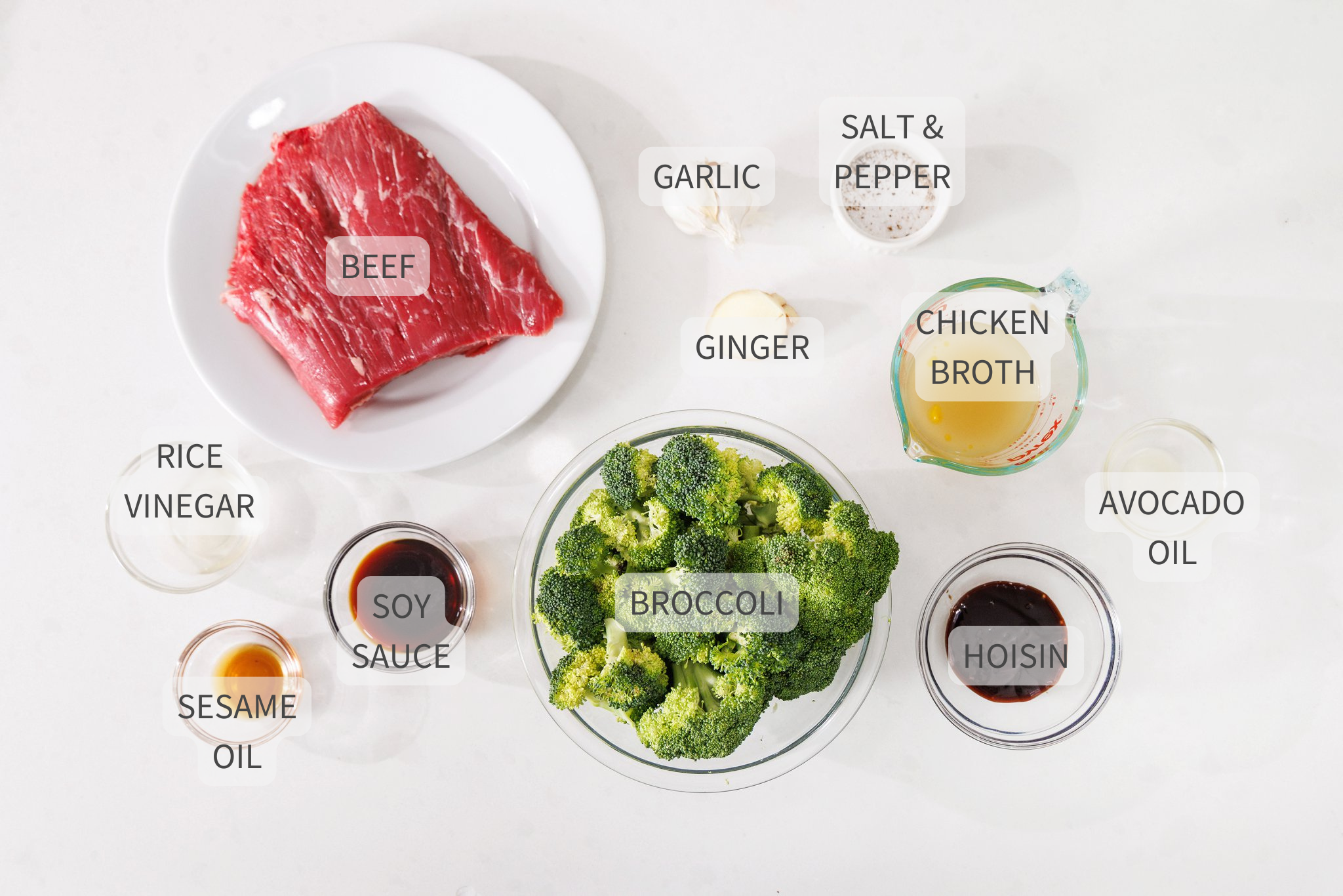 Labeled ingredients for beef and broccoli on a white counter.