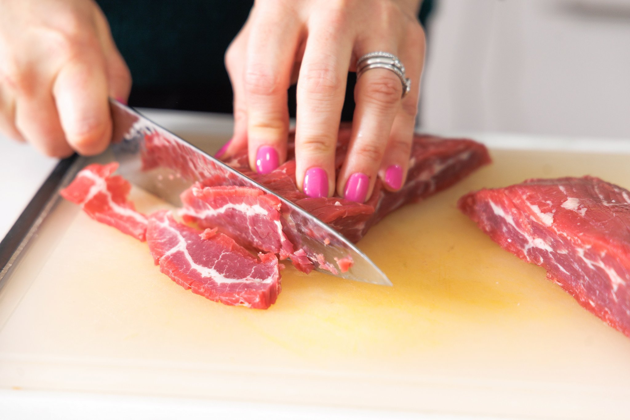 Liz slicing beef sirloin into thin strips with a sharp knife.